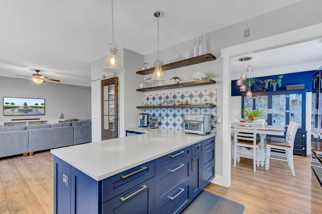 kitchen with blue cabinetry, kitchen peninsula, ceiling fan, and pendant lighting