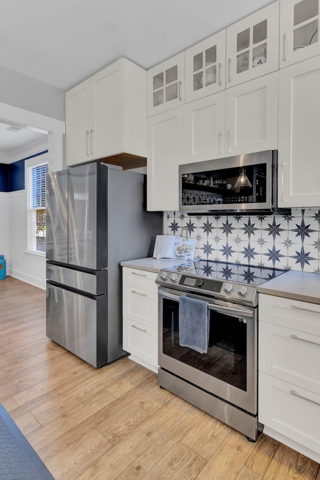 kitchen featuring tasteful backsplash, white cabinets, and appliances with stainless steel finishes