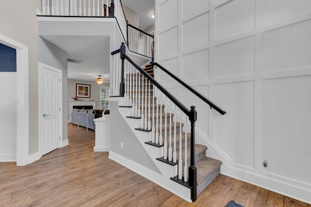 stairs with wood-type flooring and ceiling fan