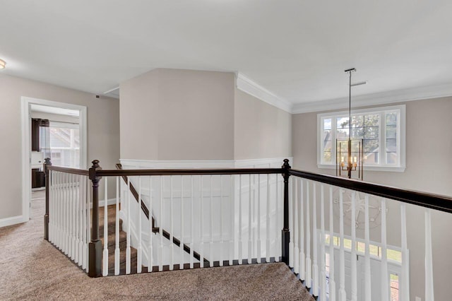 corridor featuring carpet flooring, crown molding, and a chandelier