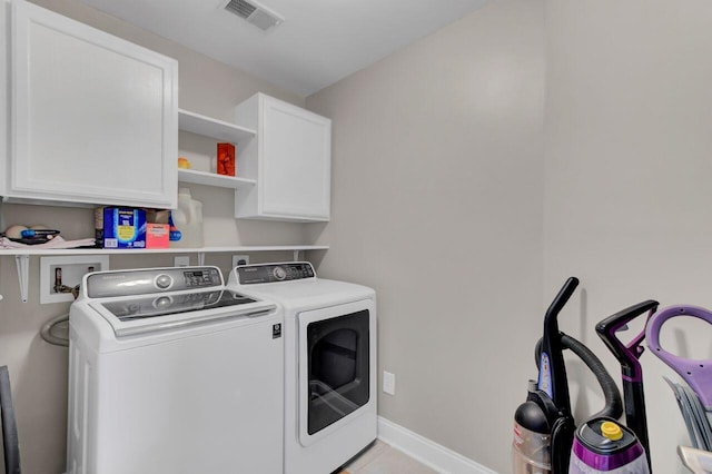 laundry room featuring washing machine and clothes dryer, light tile patterned floors, and cabinets