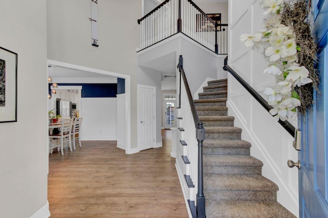 stairway featuring wood-type flooring and a high ceiling