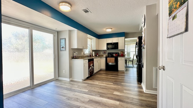 kitchen featuring black appliances, light wood finished floors, a textured ceiling, baseboards, and white cabinetry