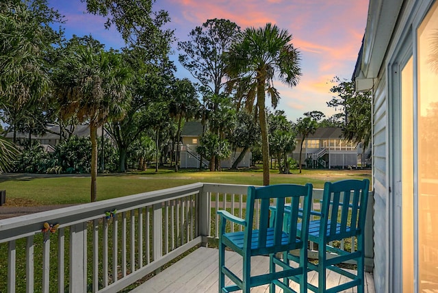 deck at dusk featuring a yard