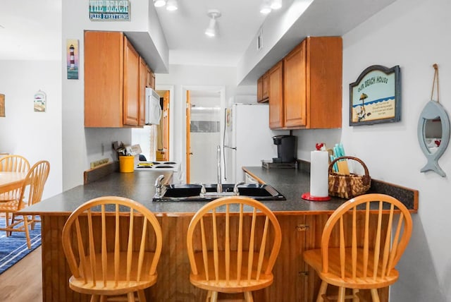 kitchen with a peninsula, a breakfast bar, and dark countertops