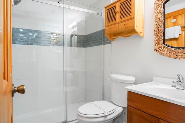 bathroom with toilet, a stall shower, and vanity