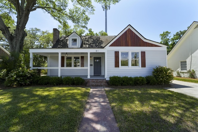 view of front of home featuring a porch, a front lawn, and a chimney