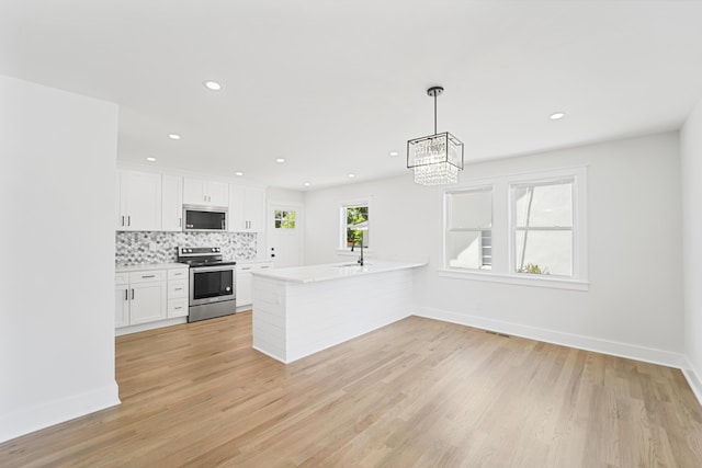 kitchen with light countertops, stainless steel appliances, baseboards, white cabinetry, and tasteful backsplash