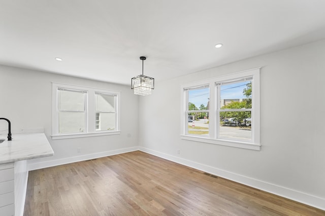 unfurnished dining area with light wood-style floors, visible vents, baseboards, an inviting chandelier, and recessed lighting