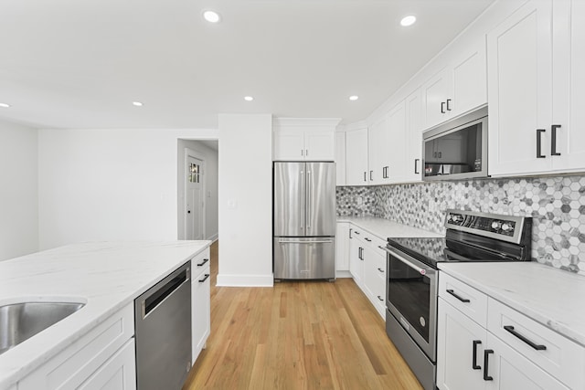 kitchen with recessed lighting, white cabinets, light wood-style flooring, backsplash, and stainless steel appliances
