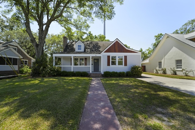 view of front of house featuring covered porch, a chimney, and a front yard