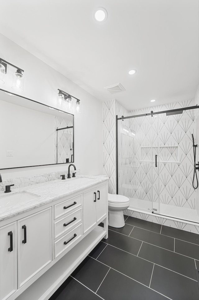 bathroom featuring double vanity, toilet, a shower stall, and a sink