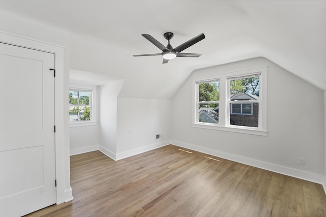 additional living space featuring visible vents, baseboards, ceiling fan, light wood-style flooring, and vaulted ceiling