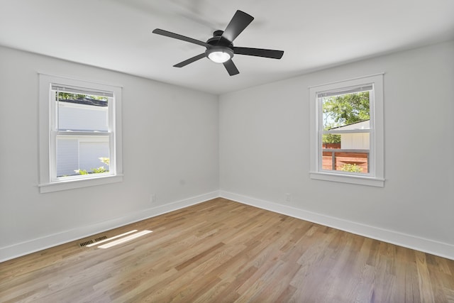 spare room featuring baseboards, plenty of natural light, and light wood finished floors