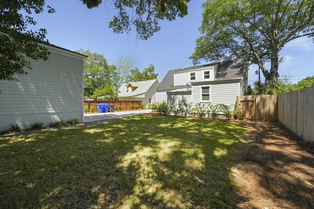 rear view of house with fence and a lawn