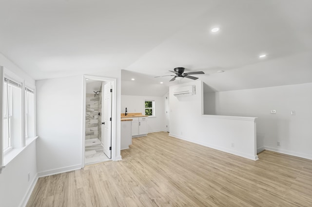 unfurnished bedroom with light wood-style floors, a wall mounted AC, recessed lighting, and lofted ceiling