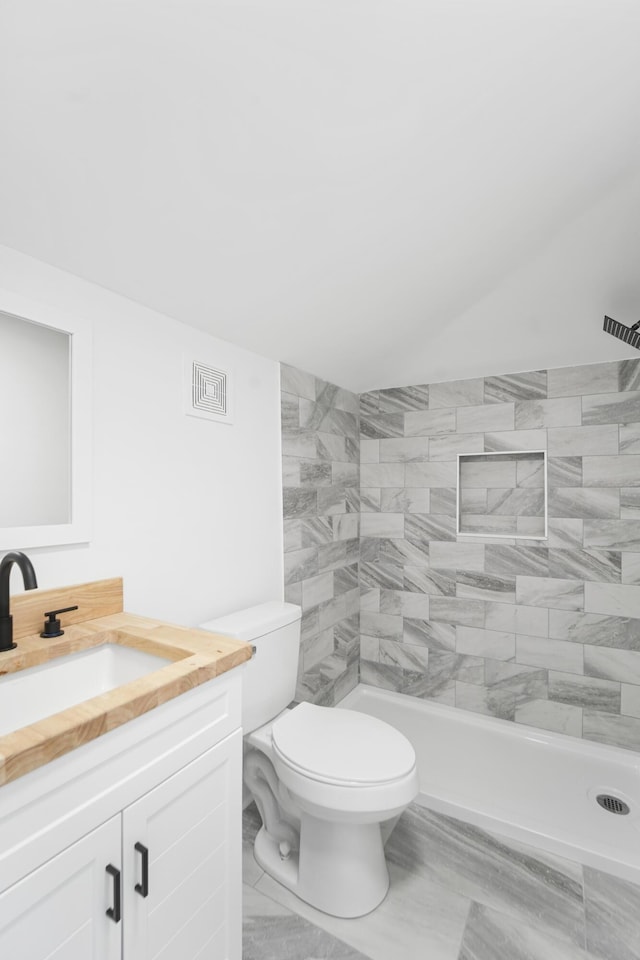 full bath featuring toilet, visible vents, a tile shower, and vanity