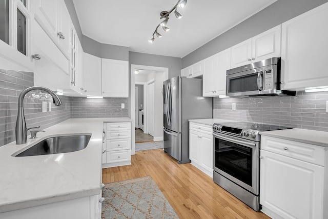 kitchen featuring white cabinetry, sink, decorative backsplash, light hardwood / wood-style floors, and stainless steel appliances