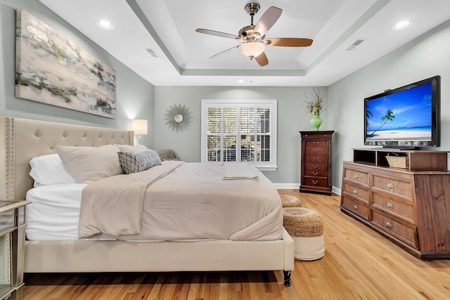 bedroom featuring a tray ceiling, light hardwood / wood-style floors, and ceiling fan