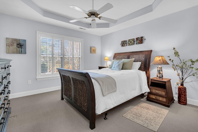 bedroom with dark carpet, a raised ceiling, and ceiling fan