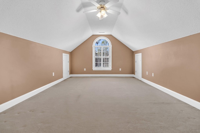 bonus room with ceiling fan, lofted ceiling, carpet, and a textured ceiling