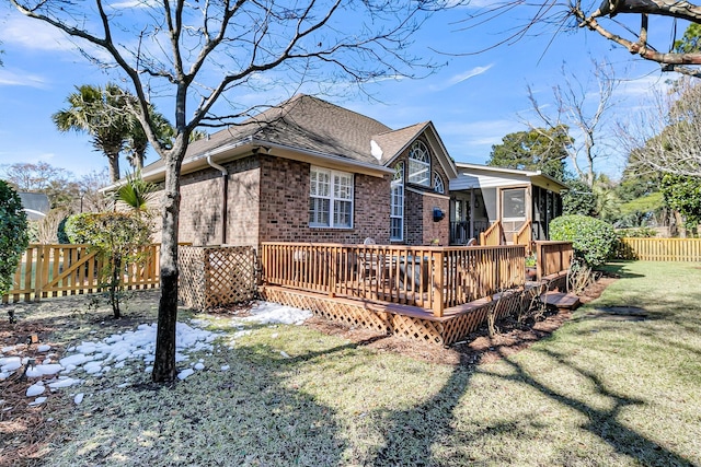 back of property featuring a wooden deck and a lawn