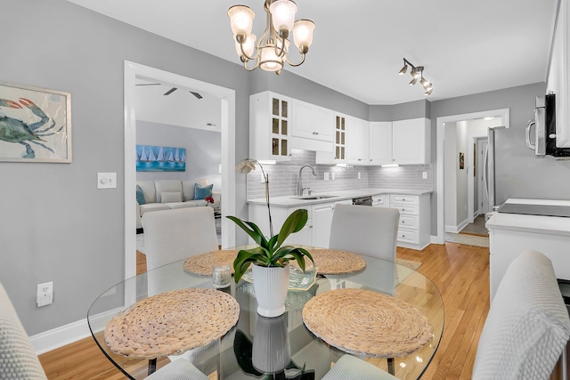 dining area with light hardwood / wood-style floors, sink, and a notable chandelier