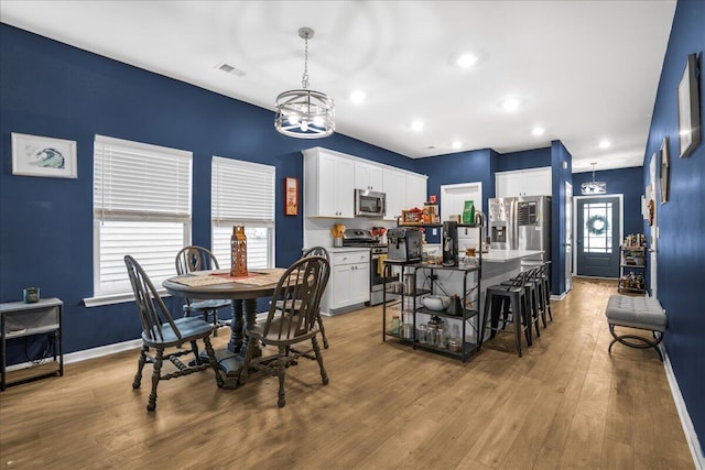 dining space with light wood-type flooring and an inviting chandelier