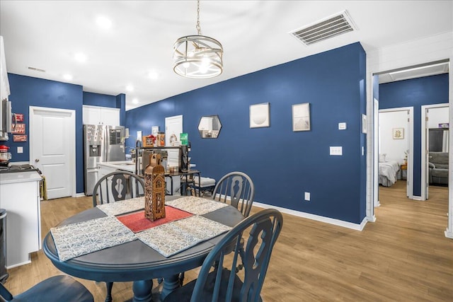 dining space featuring sink, light hardwood / wood-style floors, and an inviting chandelier