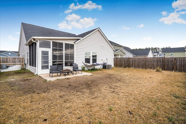 back of house featuring a sunroom, a yard, an outdoor fire pit, and a patio