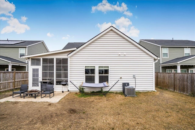 back of property with central air condition unit, a fire pit, a lawn, and a sunroom