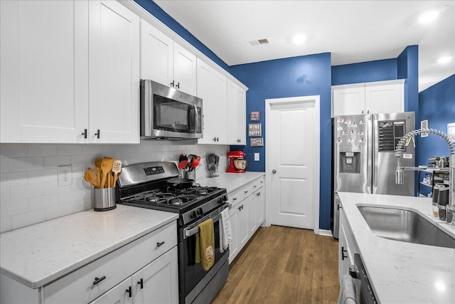 kitchen with dark wood-type flooring, white cabinets, stainless steel appliances, and sink