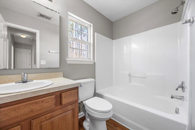 full bathroom with hardwood / wood-style floors, toilet, a textured ceiling, vanity, and shower / bathing tub combination