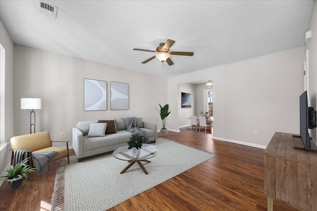 living room featuring a textured ceiling, ceiling fan, and dark hardwood / wood-style flooring