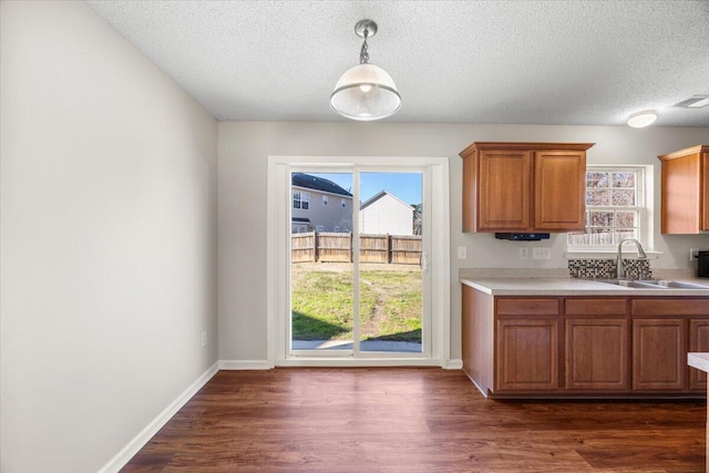 kitchen with decorative light fixtures, sink, a textured ceiling, and dark wood-type flooring