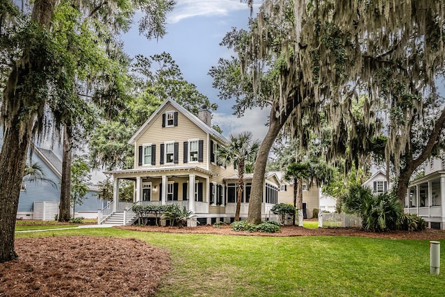 view of front of home with a porch, a front lawn, and a sunroom