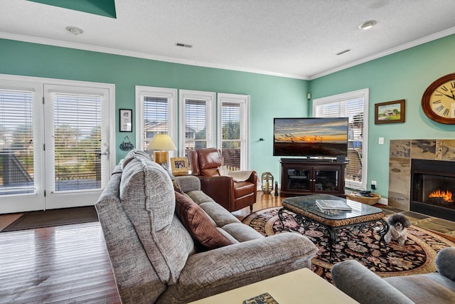 living room featuring a wealth of natural light, a fireplace, a textured ceiling, and hardwood / wood-style flooring