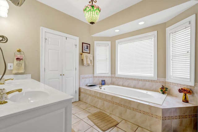 bathroom featuring vanity, plenty of natural light, a relaxing tiled tub, and tile patterned flooring