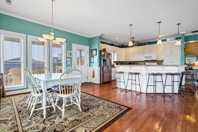 dining area featuring ornamental molding, ceiling fan with notable chandelier, and dark wood-type flooring