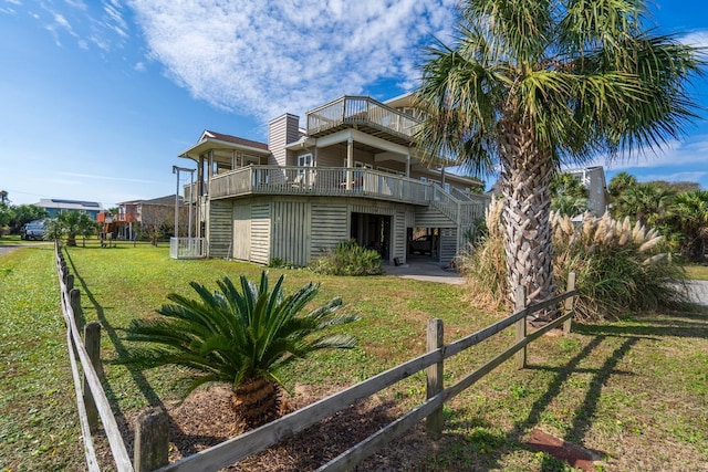 rear view of property featuring a balcony and a lawn