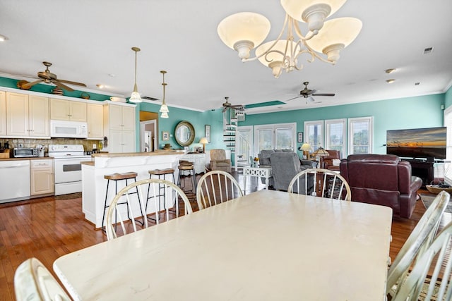 dining space with dark hardwood / wood-style floors, ornamental molding, and ceiling fan with notable chandelier