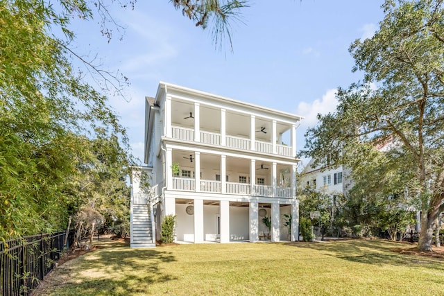 back of property with a lawn, a balcony, and ceiling fan