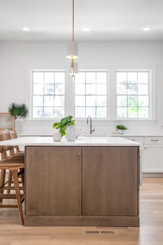 kitchen featuring white cabinetry, a kitchen bar, a wealth of natural light, and pendant lighting