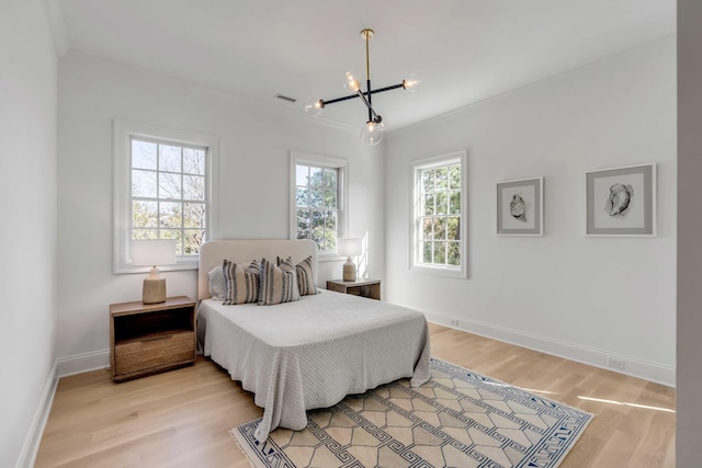 bedroom with ornamental molding, a notable chandelier, and light wood-type flooring