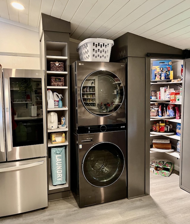 washroom featuring light wood-style flooring, wood ceiling, stacked washer / dryer, and laundry area