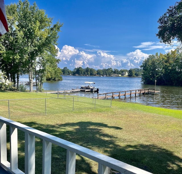 view of yard featuring a dock, a water view, and fence