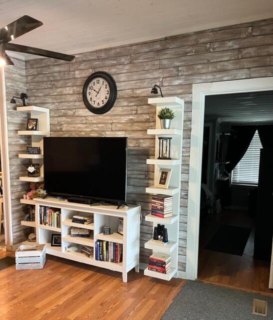 living area featuring wooden walls and wood finished floors