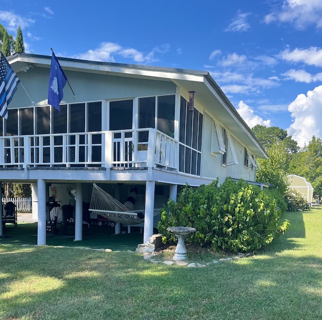 back of house with a lawn, a sunroom, a carport, and a deck