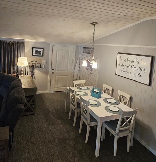 carpeted dining area featuring wood ceiling, vaulted ceiling, baseboards, and wooden walls