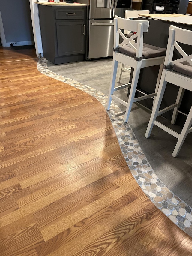 interior space featuring refrigerator, dark cabinetry, and light wood-style flooring